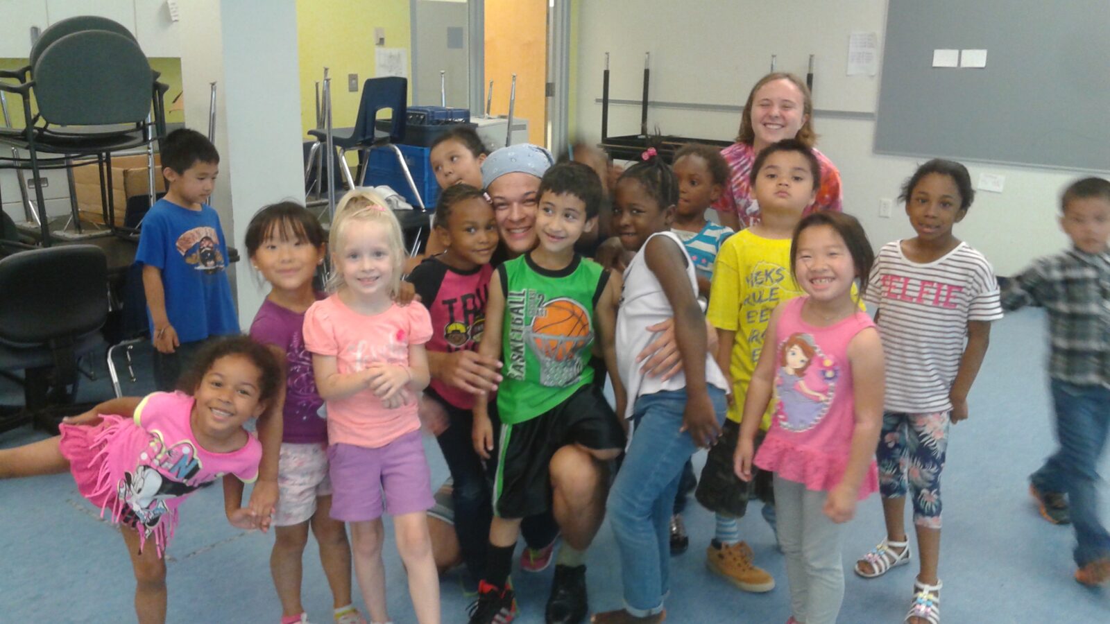 Smiling adult posing with classroom of happy kids