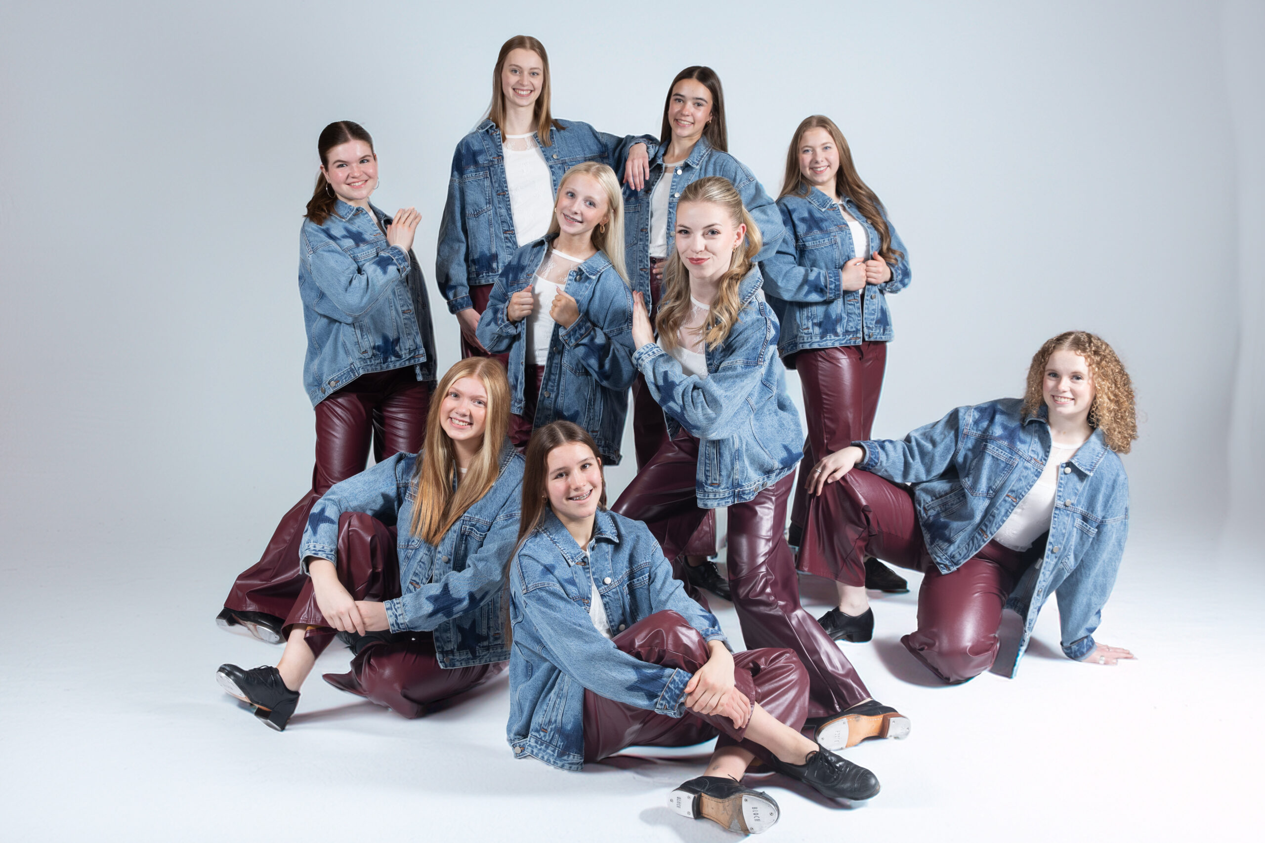 Ten dancers from Keane Sense of Rhythm posing for a picture wearing blue denim jackets with stars and burgandy leather pants