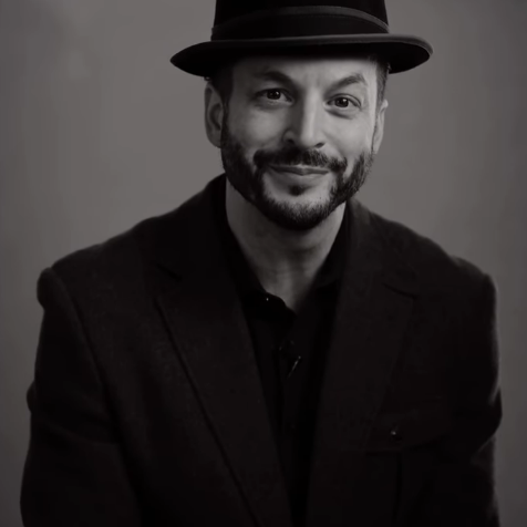 A headshot of tap dancer Ricci Milan wearing a hat